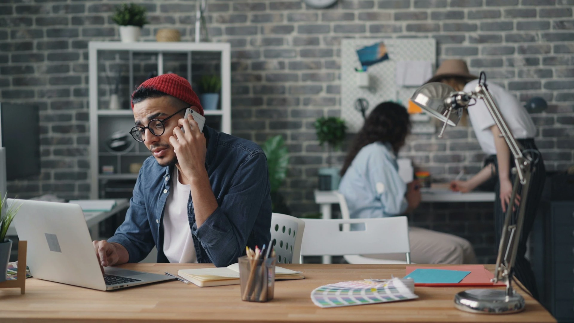 a man sitting at a desk talking on a cell phone
