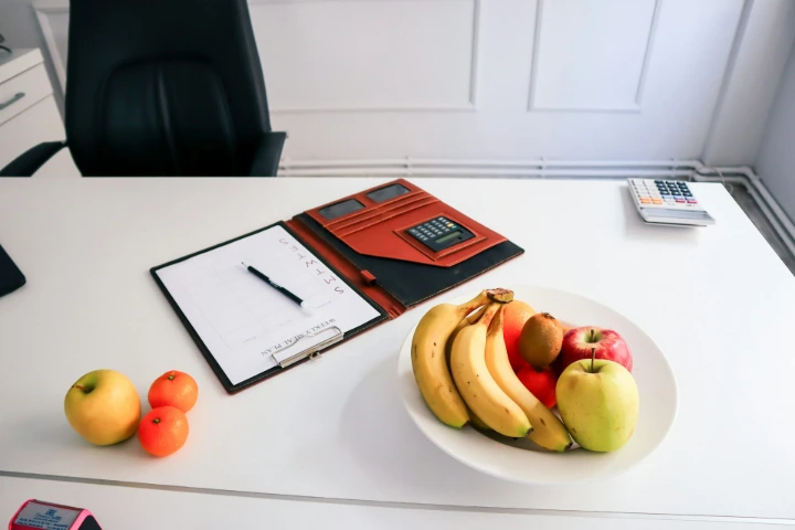 a plate of fruit and a clipboard on a desk